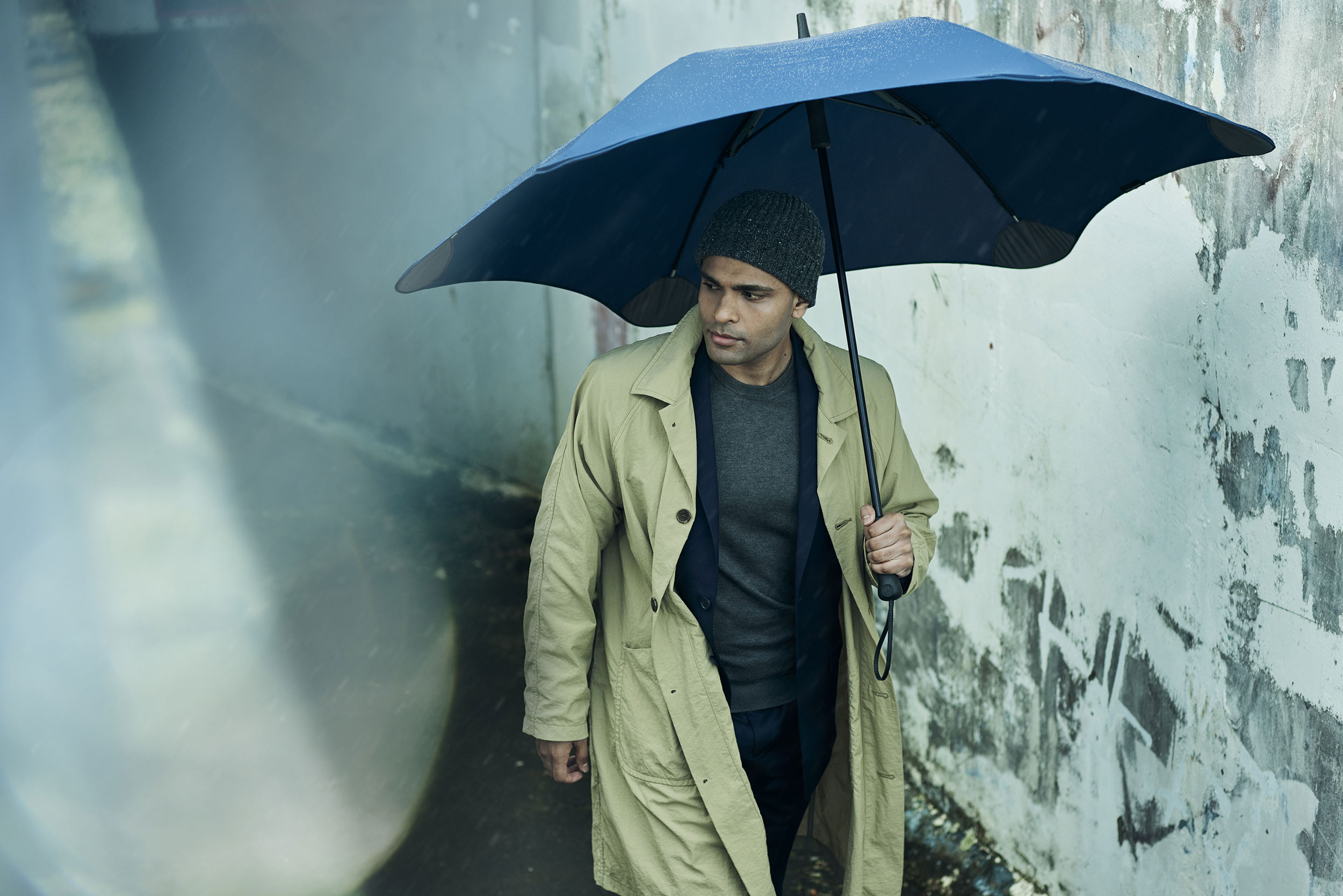 Man in trenchcoat in tunnel with umbrella BLUNT