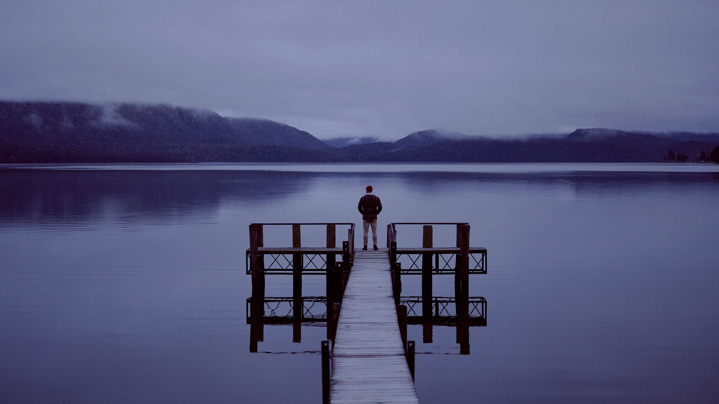 Swanndri Winter man standing at Te Anau lake edge mountains